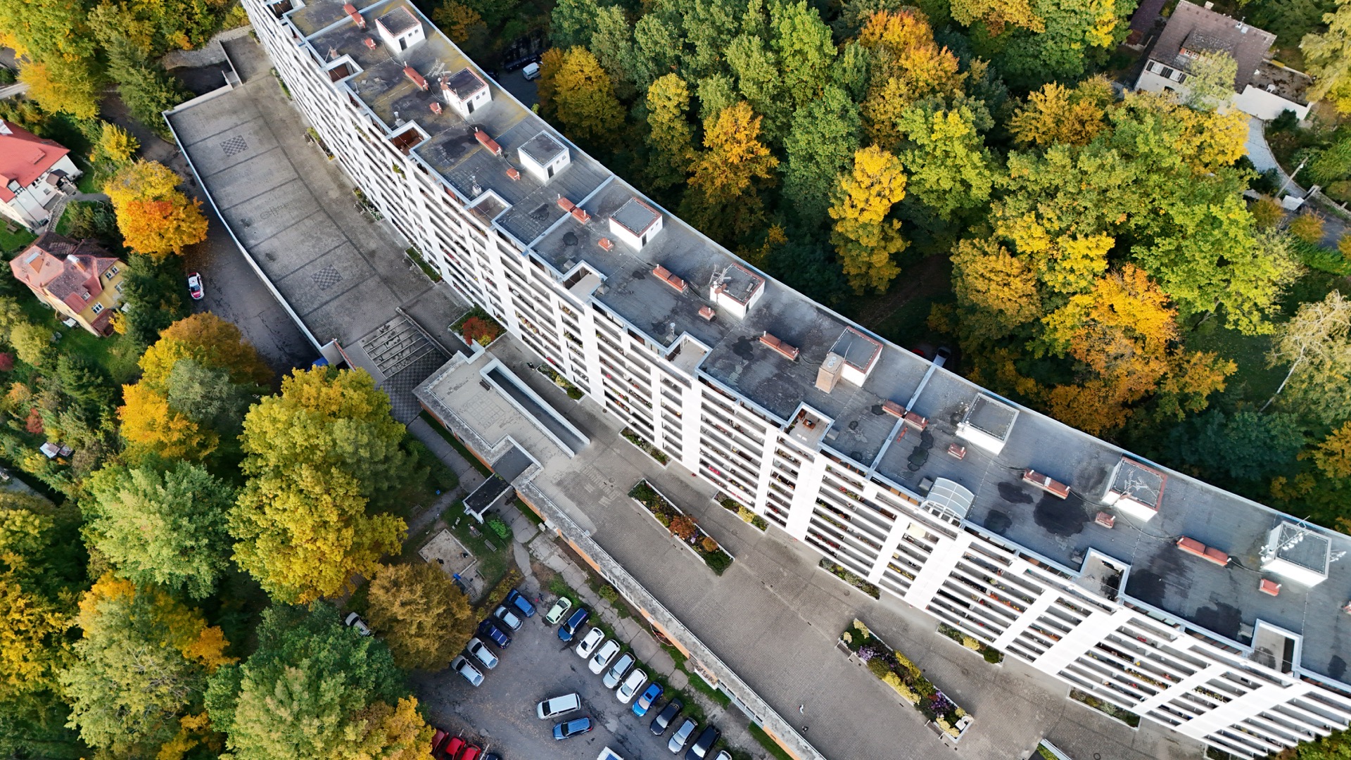 Letecký pohled na bytový dům obklopený podzimními stromy