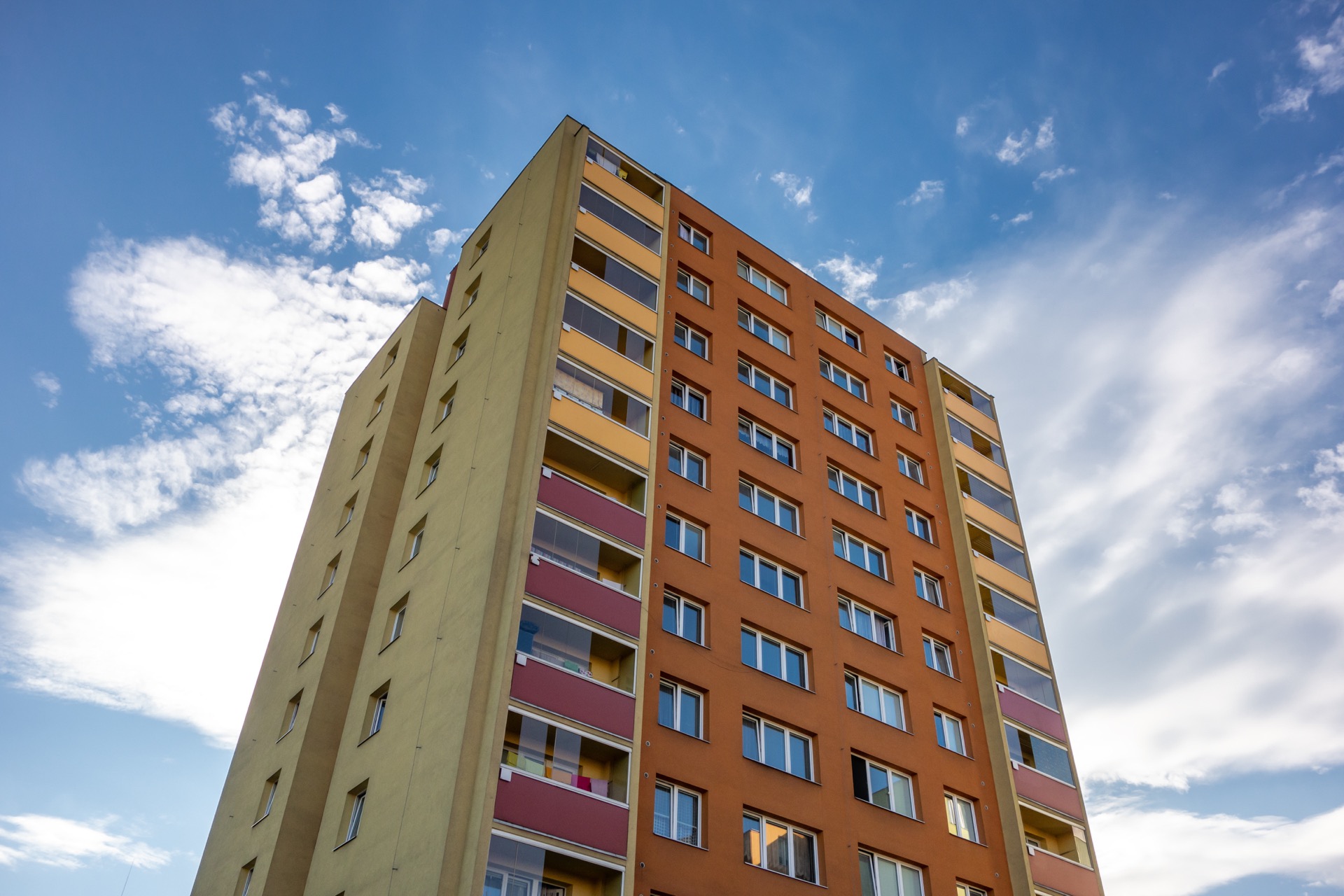 Barevný bytový dům s balkony pod modrou oblohou